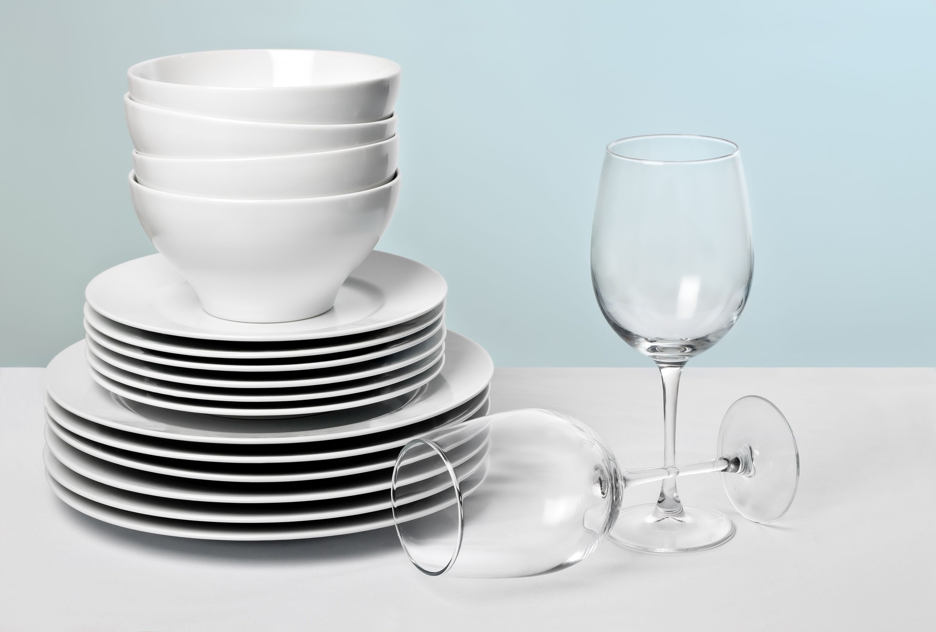 White dishes and crystal wine glasses on varied blue background